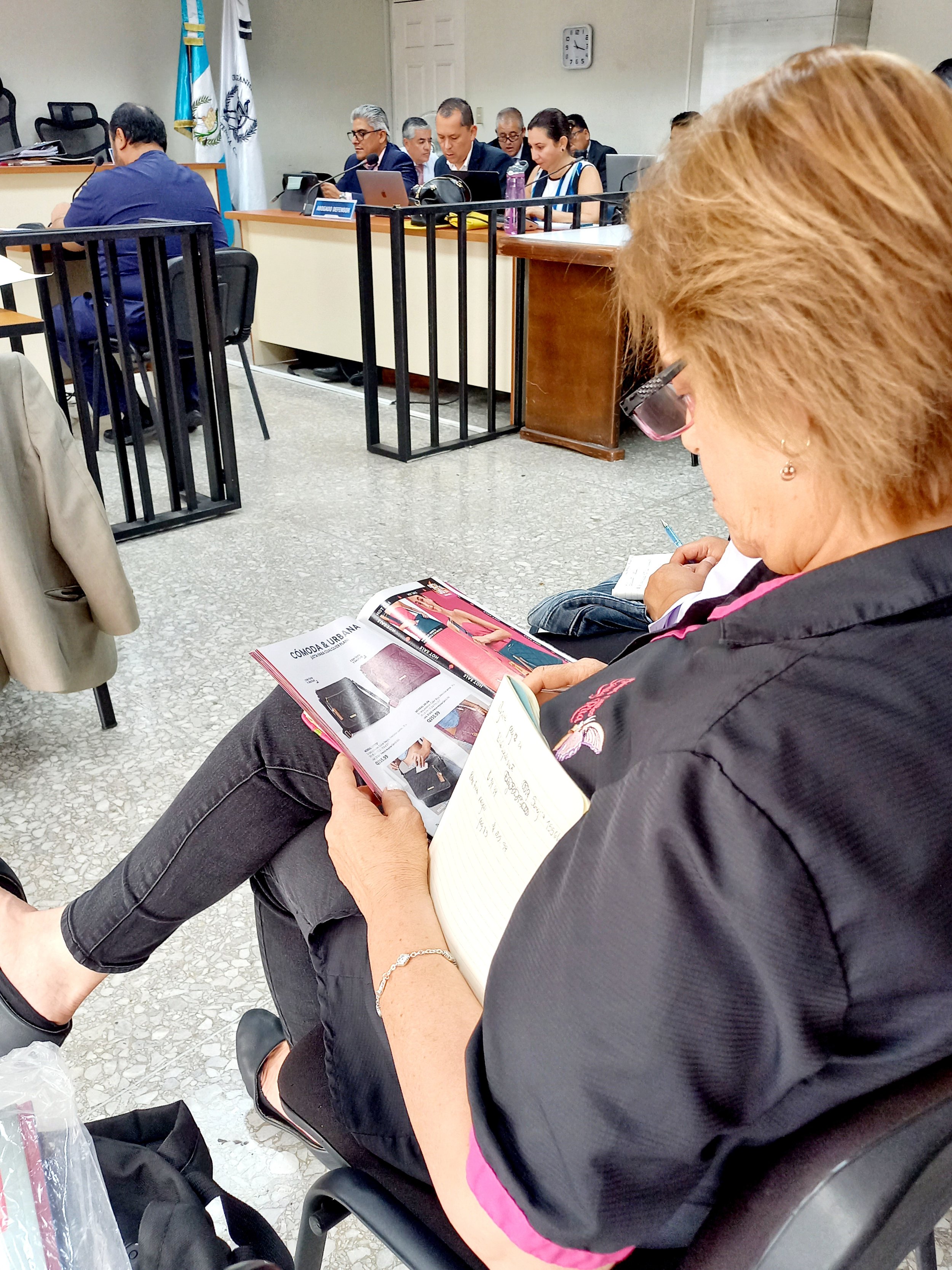  Foto: Anaí Keller, una de las acusadas, ve una revista de artículos por catálogo mientras se desarrolla la audiencia.  